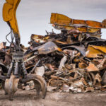 Large tracked excavator working a steel pile at a metal recycle yard, France